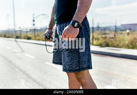 La sezione centrale del giovane sportivo uomo su una strada con corda Foto Stock