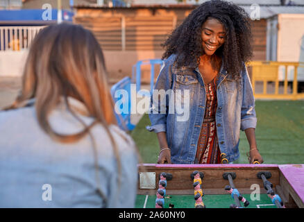Ritratto di felice giovane donna tavolo da gioco a calcio con il suo amico Foto Stock