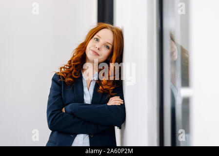 Ritratto di redheaded imprenditrice appoggiato contro una parete Foto Stock