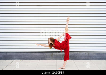 Sporty giovane donna facendo acrobazie all'aperto Foto Stock