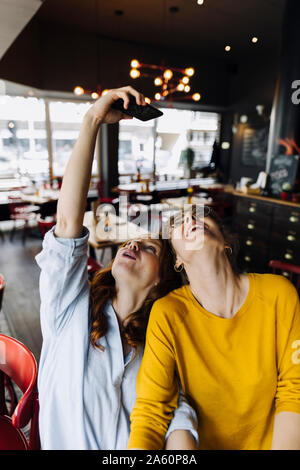 Due happy amici di sesso femminile prendendo un selfie in un ristorante Foto Stock