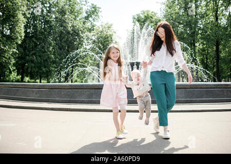 Madre e figlia e baby boy vicino a una fontana Foto Stock