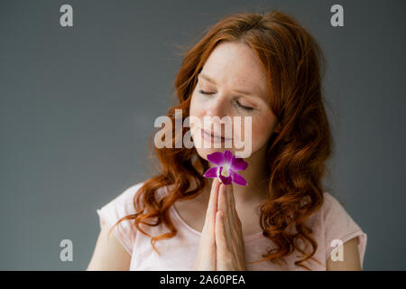 Ritratto di donna redheaded con viola fioritura di orchidee Foto Stock