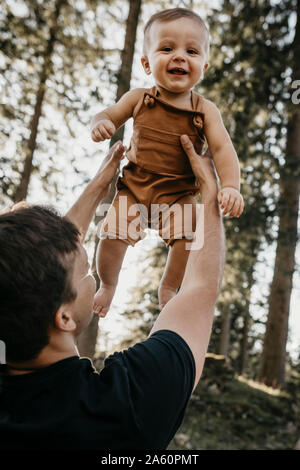 Padre Felice sollevamento piccolo figlio su una escursione in una foresta, Schwaegalp, Nesslau, Svizzera Foto Stock
