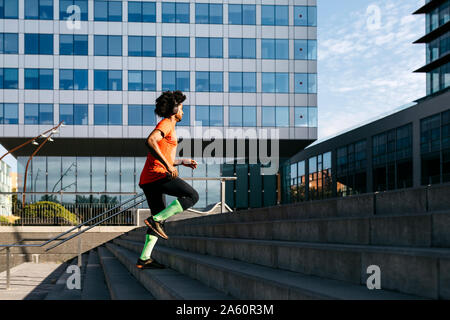 Giovane uomo jogging in città, l'ascolto di musica Foto Stock