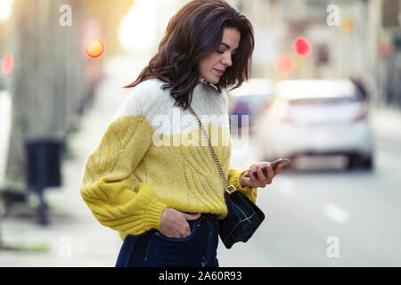 Brunette donna che usa il suo smartphone nella città Foto Stock