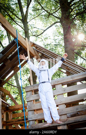 Ragazzo giovane come un supereroe, astronauta giocando in un albero di casa Foto Stock