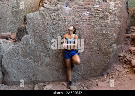 Giovane donna asiatica di arrampicata in una parete di roccia Foto Stock