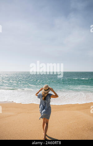 Vista posteriore della donna di camminare sulla spiaggia, nazare, Portogallo Foto Stock