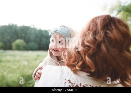 Felice bambina cerca su madre della spalla Foto Stock