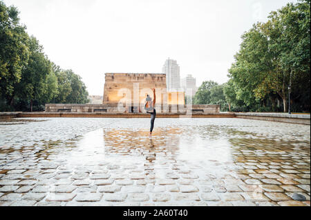 Donna pratica lo yoga sotto la pioggia, posizione ballerino Foto Stock