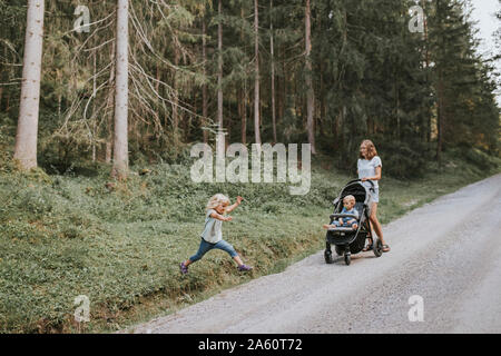 La madre con la figlia e il bambino nel passeggino in foresta Foto Stock