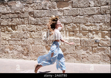 Felice giovane donna che corre lungo una parete Foto Stock