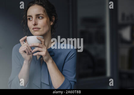 Ritratto di giovane donna rilassante con tazza di caffè Foto Stock