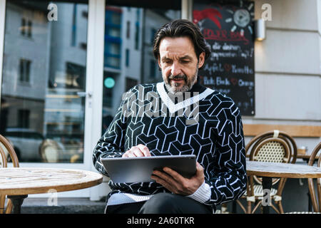 Ritratto di moda uomo maturo con tavoletta digitale a pavement cafe Foto Stock
