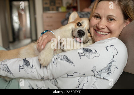 Ritratto di donna felice cuddling con il suo cane a casa Foto Stock