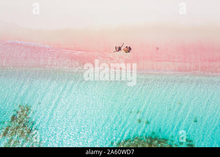 L uomo e la donna per divertirsi a volare un drone sulla sabbia rosa beach, Caraibi, Antille, West Indies, America Centrale Foto Stock