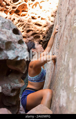 Giovane donna asiatica di arrampicata in una parete di roccia Foto Stock