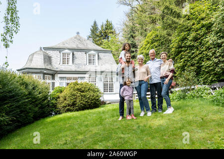 Felice famiglia estesa in piedi nel giardino della loro casa Foto Stock