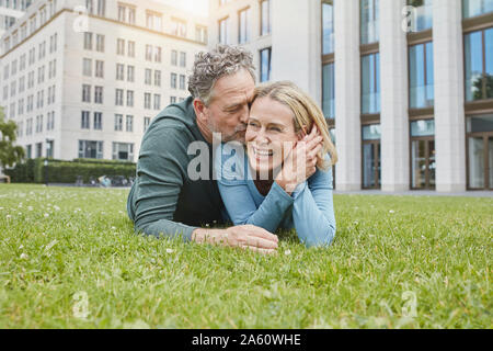 Felice Coppia matura giacente sul prato in città Foto Stock