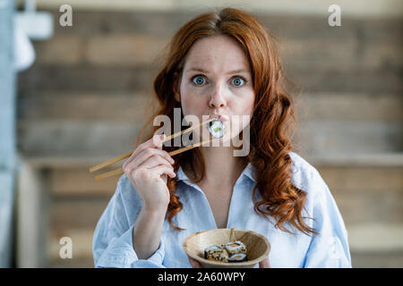 Ritratto di donna redheaded mangiare sushi Foto Stock