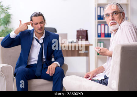 Il giovane uomo visitando il vecchio medico maschio psicologo Foto Stock