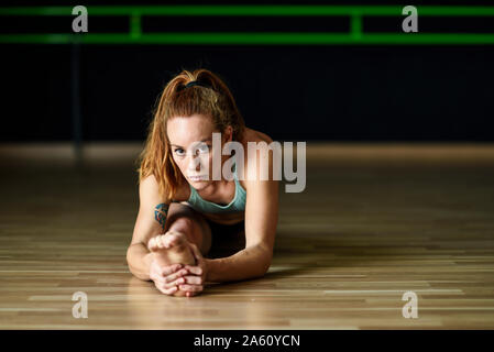 Sporty giovane donna stretching in palestra Foto Stock