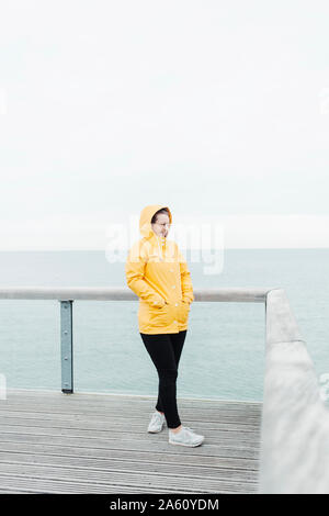 Giovane donna indossa giallo cappotto di pioggia Foto Stock