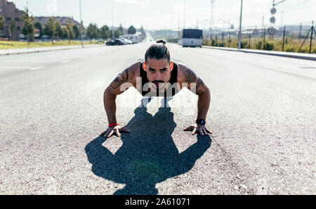 Giovane uomo che fa spingere ups su una strada Foto Stock