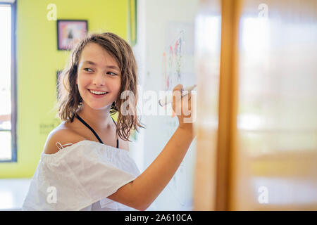 Ritratto di ragazza sorridente disegno su una lavagna bianca Foto Stock