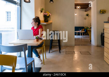 Giovane donna utilizzando laptop in un cafe Foto Stock