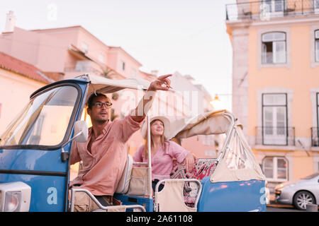 Un Tuk Tuk driver fornendo il tour della città per un turista, Lisbona, Portogallo Foto Stock