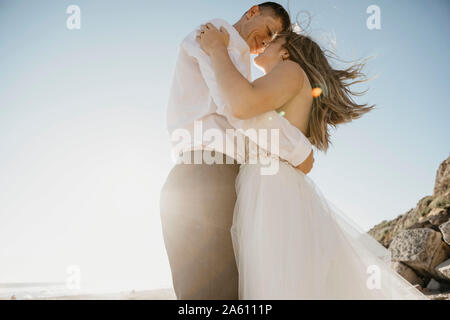 Affettuosa sposa e lo sposo sulla spiaggia al tramonto Foto Stock