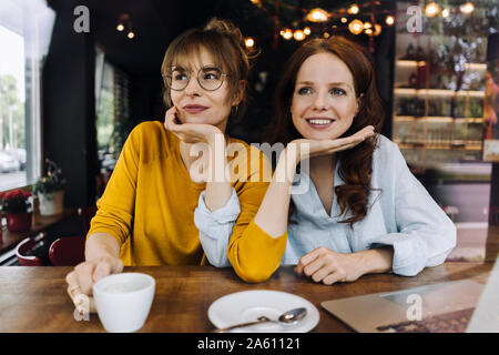 Due amiche con il computer portatile in un cafe Foto Stock