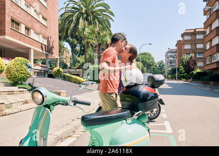 Coppia giovane kissing a un vintage scooter Foto Stock