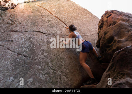 Giovane donna asiatica di arrampicata in una parete di roccia Foto Stock