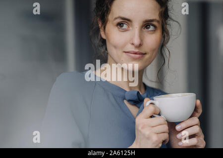 Ritratto di giovane donna rilassante con tazza di caffè Foto Stock