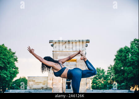 Donna pratica lo yoga sotto la pioggia, posizione ballerino Foto Stock