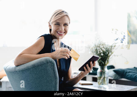 Imprenditrice rendendo il pagamento on-line, utilizza lo smartphone e la carta di credito in un coffe shop Foto Stock