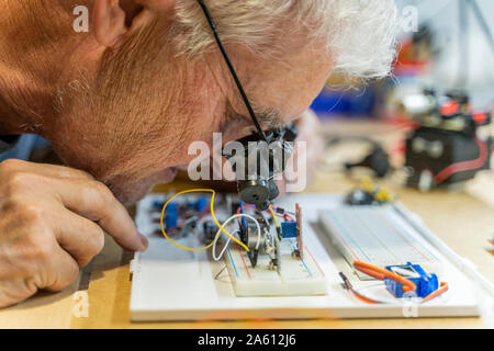 Senior uomo al lavoro su circuiti elettronici nella sua officina Foto Stock