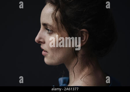 Profilo di giovane donna contro uno sfondo scuro Foto Stock