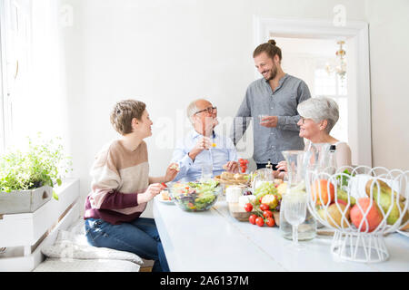 Felice coppia senior con figli adulti aventi il pranzo a casa Foto Stock