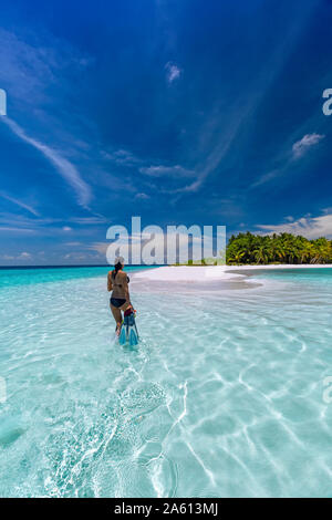 Donna con equipaggiamento da snorkelling sulla spiaggia tropicale, Maldive, Oceano Indiano, Asia Foto Stock