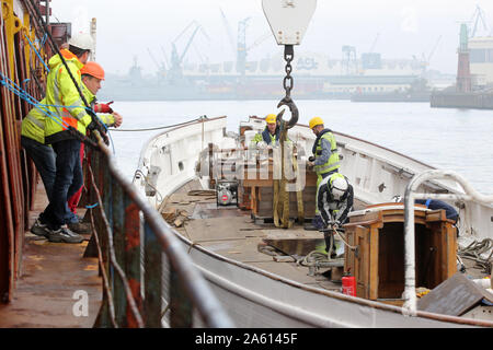 Amburgo, Germania. 23 Ott, 2019. I dipendenti stanno preparando per caricare il pilota goletta "No.5 Elba' nel porto di Amburgo su un coaster. La goletta sarà quindi trasportati al cantiere navale danese 'Hvide Sande cantiere". Il 'n. 5 Elbe" era entrato in collisione con una nave portacontainer sull'Elba su Giugno 8, 2019 con 43 persone a bordo, ma aveva reso ad un molo nel Schwinge bocca dove si affondò e fu recuperato dopo breve tempo. Credito: Bodo segna/dpa/Alamy Live News Foto Stock