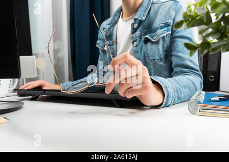 Donna che lavorano presso il suo ufficio a casa, hipster ragazza scrittura freelance sul computer e tenendo i bicchieri in mano. Il concetto di business Foto Stock