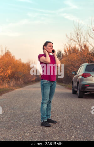 La donna perse durante il car guida attraverso la campagna parlando al telefono cellulare tenta di ottenere aiuto e assistenza stradale Foto Stock