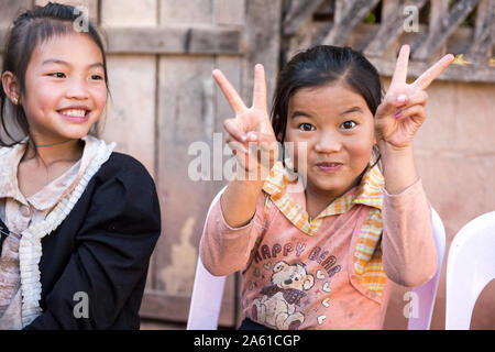 I bambini in un villaggio Khmu in Laos si riuniscono intorno a un tavolo, gustando uno spuntino condiviso e momenti di gioia insieme. Foto Stock