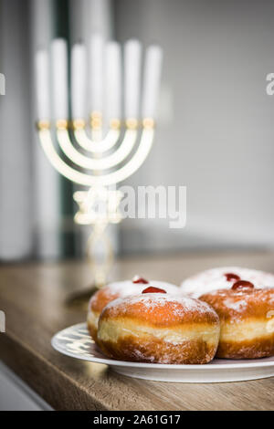 Jewish Hanukkah menorah e ciambelle sufganiyot sul tavolo di legno Foto Stock