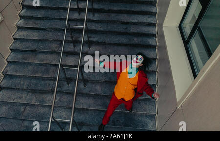 Dnipro, Ucraina - 22 Ottobre 2019: Cosplayer a immagine di un pazzo clown Arthur Fleck dal thriller psicologico 'Joker' scorre giù per le scale. Foto Stock