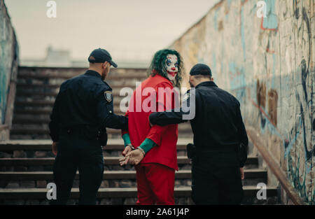 Dnipro, Ucraina - 22 Ottobre 2019: due poliziotti raffigura arresto di cosplayer a immagine di un pazzo clown Arthur Fleck da quello psicologico thril Foto Stock